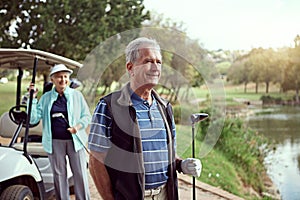 Enjoying a sunny day game. a smiling senior couple enjoying a day on the golf course.