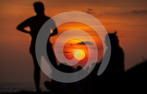 Enjoying the sunset view on the tropical beach in Galle. Silhouetted group of people in the foreground