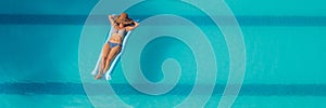 Enjoying suntan. Vacation concept. Top view of slim young woman in bikini on the blue air mattress in the big swimming pool BANNER
