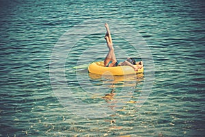 Enjoying suntan. Vacation concept. Top view of slim young woman in bikini holding yellow air mattress.