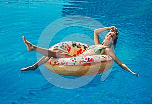 Enjoying suntan Woman in bikini on the inflatable mattress in the swimming pool.