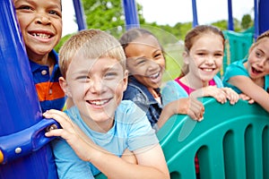 Enjoying their vacation together. A multi-ethnic group of happy children playing on a jungle gym in a play park.