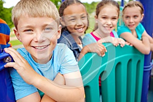 Enjoying time spent with his friends. A multi-ethnic group of happy children playing on a jungle gym in a play park.