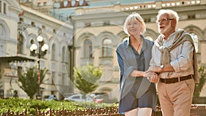 Enjoying time together. Happy and beautiful elderly couple holding hands while walking outdoors