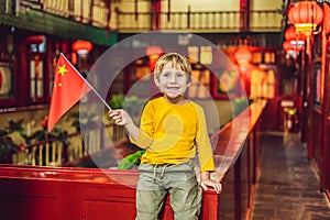 Enjoying vacation in China. Happy tourist boy with a Chinese flag on a Chinese background. Travel to China with kids
