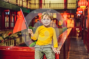 Enjoying vacation in China. Happy tourist boy with a Chinese flag on a Chinese background. Travel to China with kids