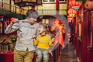 Enjoying vacation in China. Happy tourists dad and son with a Chinese flag and with traditional Chinese candied fruits