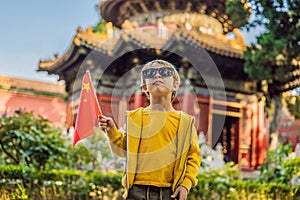 Enjoying vacation in China. Young boy with national chinese flag in Forbidden City. Travel to China with kids concept