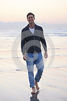 Enjoying a walk on the beach. Full-length portrait of a handsome young man walking on the beach.