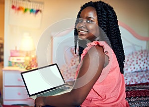 Enjoying the wifi at home. Cropped shot of an adorable little girl using a laptop while sitting on her bed in her