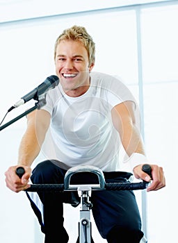 Enjoying work out at gym. Handsome man singing a song while spinning bike at the gym.