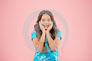 Enjoying young skin. Happy little girl touch her smooth baby skin on pink background. Small child with cute smile on