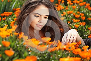 Enjoyment - free smiling woman enjoying happiness. Beautiful woman embracing in golden marigold flowers