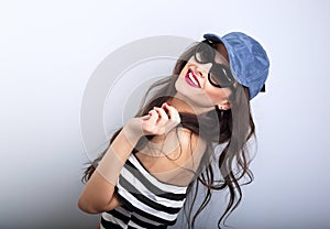 Enjoyment young woman in sunglasses and blue baseball cap posing