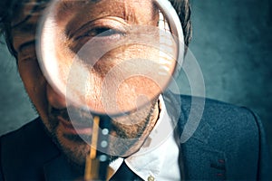 Enlarged eye of tax inspector looking through magnifying glass photo