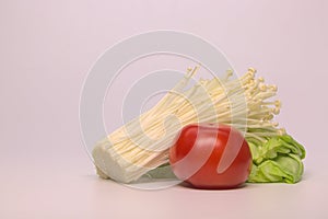 Enokitake mushrooms, tomato and lettuce isolated on pink background