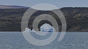 Enormous Iceberg Adrift Close to Shore in Lush Lake Landscape