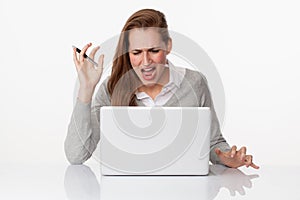 Enraged 20s woman typing on laptop on sparse white desk