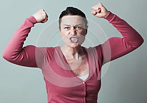 Enraged 40s woman flexing her muscles up for metaphor