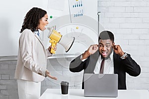 Enraged female boss with loudspeaker screaming at her scared subordinate at company office