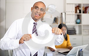 Enraged man tearing piece of paper in office
