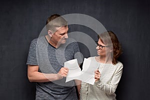 Enraged man and woman are tearing paper sheet