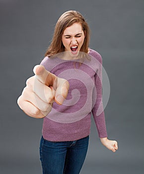 Enraged young woman screaming, pointing a bossy over sized finger