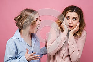 The enraged young woman screams at her friend in rage. The victim of aggression and psychological violence in fear closes her ears