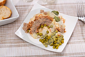 Ensalada rusa - salad with potatoes, tuna, green pea, olives and egg in plate photo