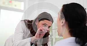 ENT clinic patient at doctor specialist otolaryngologist examines throat of young man