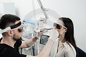 ENT doctor in protective glasses holding surgical laser and doing laser treatment inflammation of the nasal lining