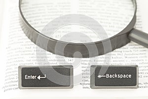Enter and Backspace Computer Keys and a Lens on a Book Page