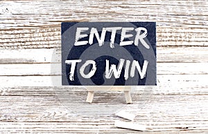 ENTER TO WIN text on the Miniature chalkboard on wooden background