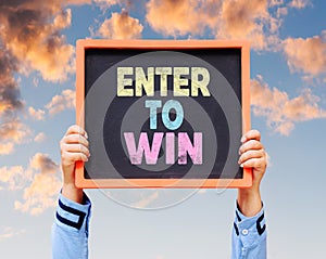 Enter To Win word on blackboard with hands are holding. photo