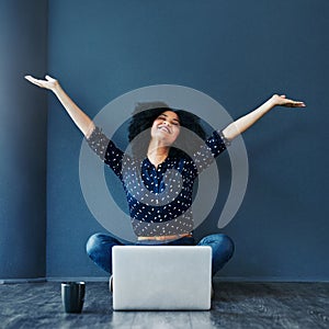 She entered, she won. Studio shot of an attractive young woman cheering while using a laptop against a blue background.