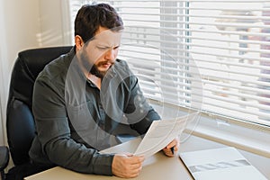 Enterpreneur working with documents at office, closed laptop on desk.