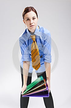 Enterpreneurs Concepts. Caucasian Female In Business Shirt and Tie Holding Batch of Folders As Hard Yoke.Against White