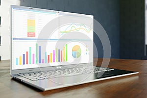 Enterprise financial report with graphs and charts on a screen of modern laptop on wooden table. Selective focus on