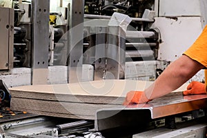 Enterprise for the production of cardboard containers . Worker put sheets of cardboard in a machine for the production