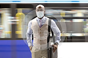 Enterprising black man wearing a face mask walking near a moving subway train