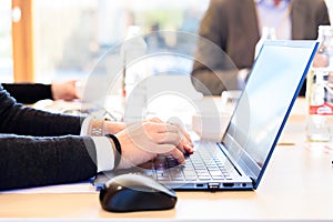 An enterprising employee types important information about her company on her laptop keyboard