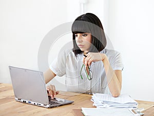 Enterprising, exceptional executive. A young pretty businesswoman working on her laptop at the office.