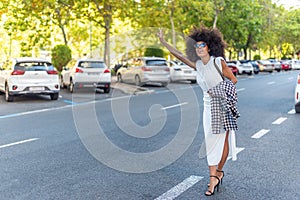 enterprising woman in a white dress hailing a taxi