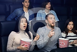 Entertainment and fun. Emotional people with popcorn watching thriller in cinema