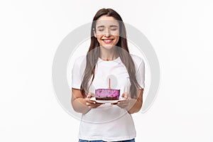 Entertainment, fun and holidays concept. Portrait of hopeful cute young girl celebrating birthday, making wish, smiling