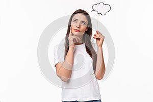 Entertainment, fun and holidays concept. Portrait of thoughtful and creative young woman searching inspiration, holding