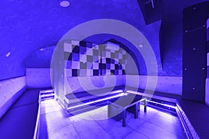 Entertainment room in a nightlife venue with rgb neon lights and continuous white seats