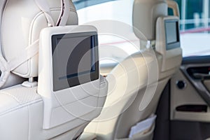 Entertainment system for rear passengers in a car with two monitors mounted on the backs of the front seats for watching TV,