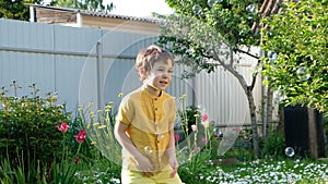 Enthusiastic active boy catches soap bubble having fun at backyard nature background medium shot happy little cute child