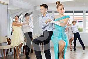 Enthusiastic adolescent girl and boy dancing in pair in dance studio